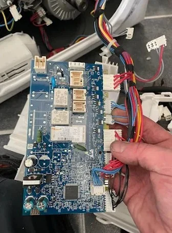 Our technician holds a new dishwasher PCB control board during a complex electronic fault repair.