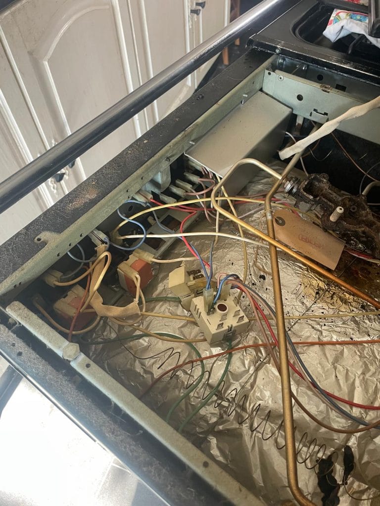 Opened top of washig machine displaying wiring and drum