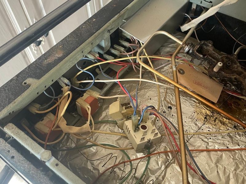 Opened top of washig machine displaying wiring and drum