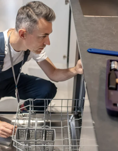 A professional appliance engineer diagnosing an integrated dishwasher fault in a Bristol kitchen using specialist tools.